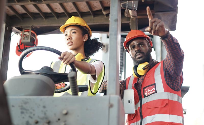 Construction workers operating machinery, one pointing directions.