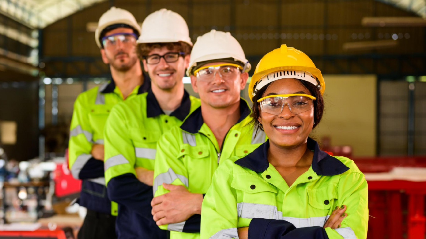 Four safety professionals wearing hard hats and eye protection smiling for the camera.